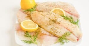 Fresh fish fillets garnished with lemon slices and dill, ready for cooking or serving.