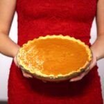 woman in red sleeveless dress holding pie