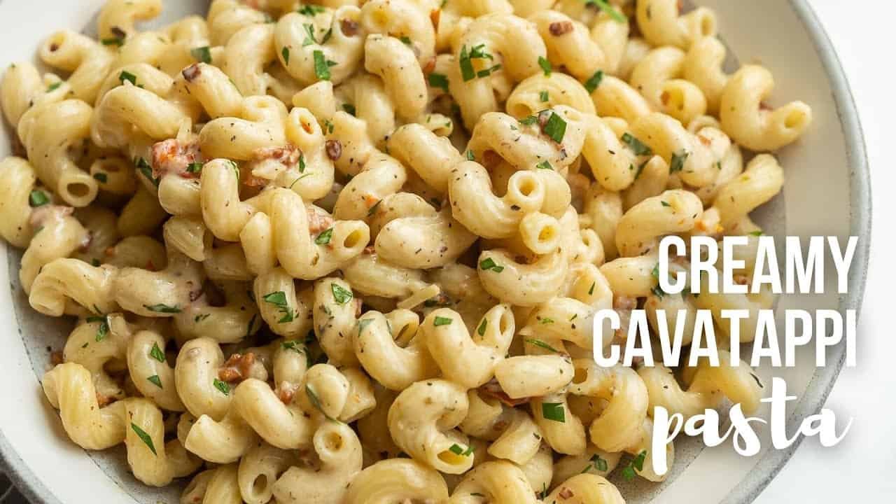 Close-up of cooked cavatappi pasta, lightly seasoned and garnished with chopped herbs, showcasing its unique spiral shape and creamy texture. Ideal for pasta dishes or salads.