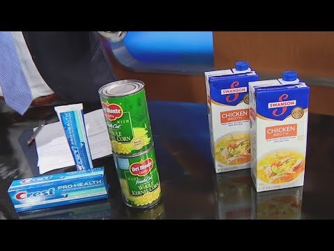 Assorted food items displayed on a table, including canned vegetables, boxed pasta, and a tube of toothpaste, highlighting grocery essentials for meal preparation and hygiene.