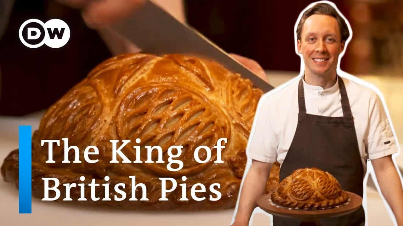 A baker in an apron holding a freshly baked golden brown pie, showcasing the craftsmanship behind traditional British pies.