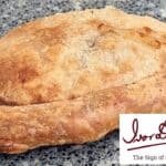 Freshly baked artisan bread on a granite surface with a logo in the corner, showcasing its rustic texture and golden crust.