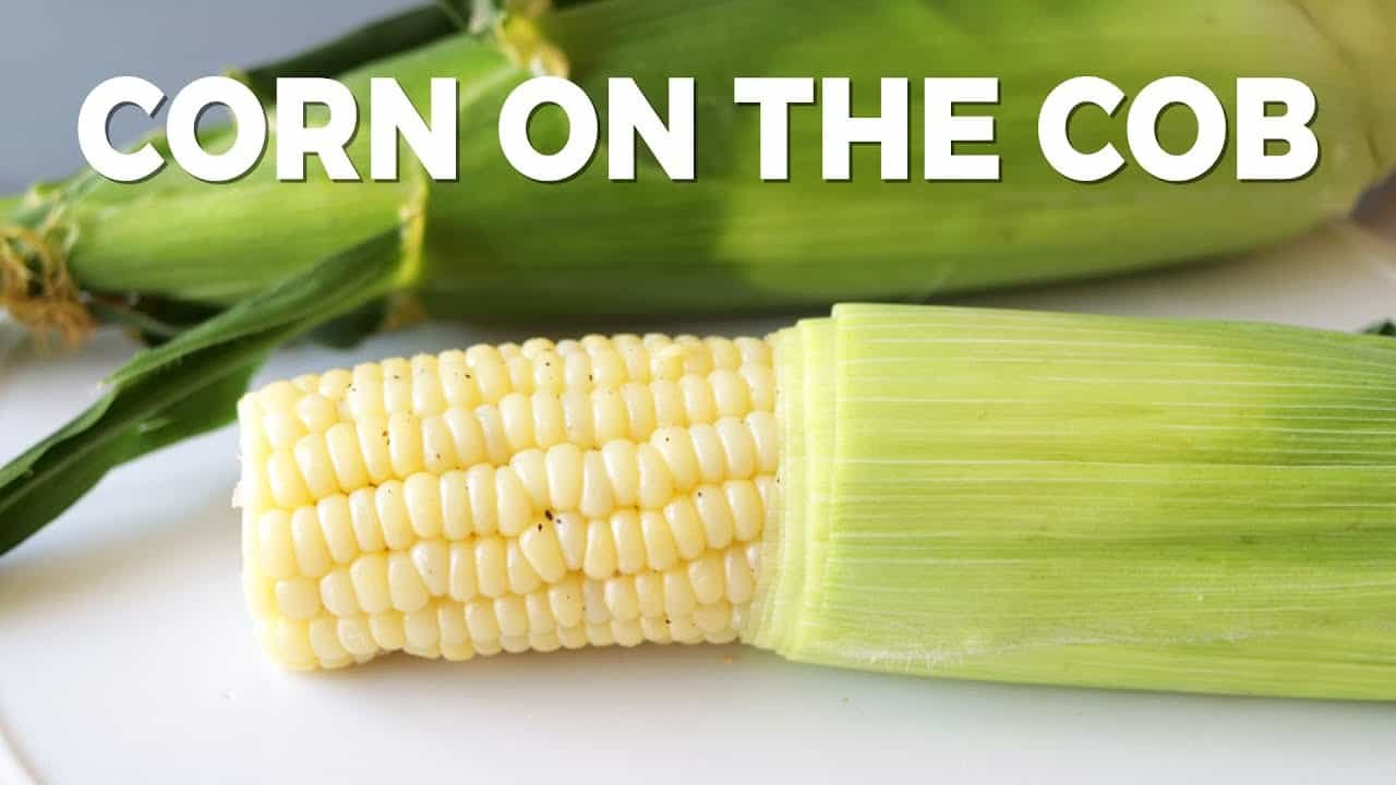 Fresh corn on the cob with green husks, showcasing plump yellow kernels and a vibrant appearance, ideal for summer recipes and grilling.