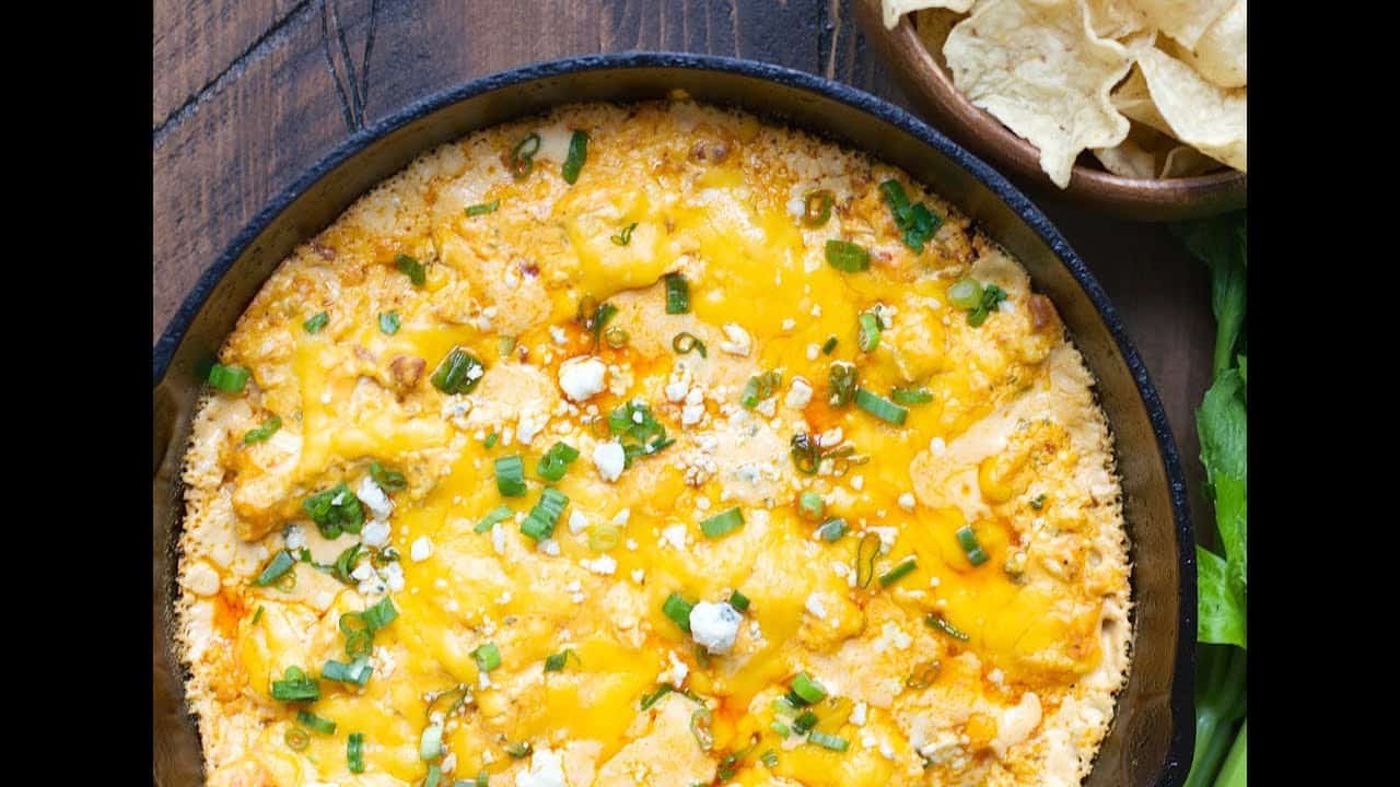 Baked cheesy dip with melted cheddar and green onions, served in a cast iron skillet, accompanied by tortilla chips. Perfect for parties and gatherings.