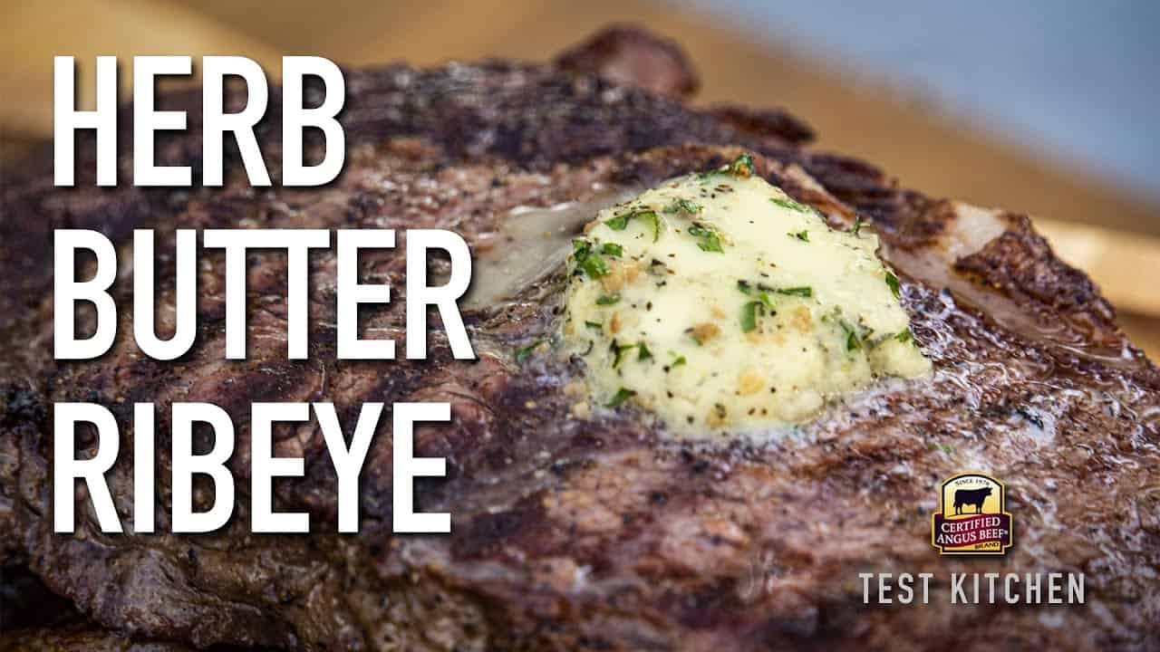 Grilled ribeye steak topped with herb butter, showcasing a perfectly cooked, juicy texture and garnished with fresh herbs, ideal for steak lovers.