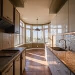 Bright and spacious kitchen with large bay windows, modern cabinetry, and a stylish backsplash, featuring ample natural light and a functional layout.