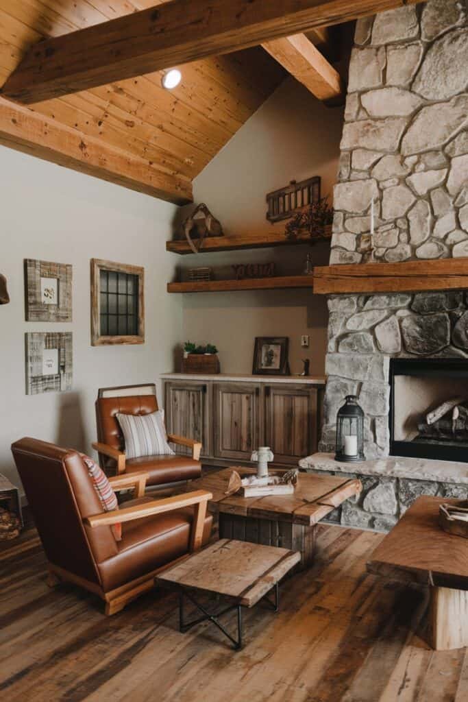 Cozy living room featuring a stone fireplace, wooden beams, and rustic decor, including leather chairs and framed artwork, creating a warm and inviting atmosphere.